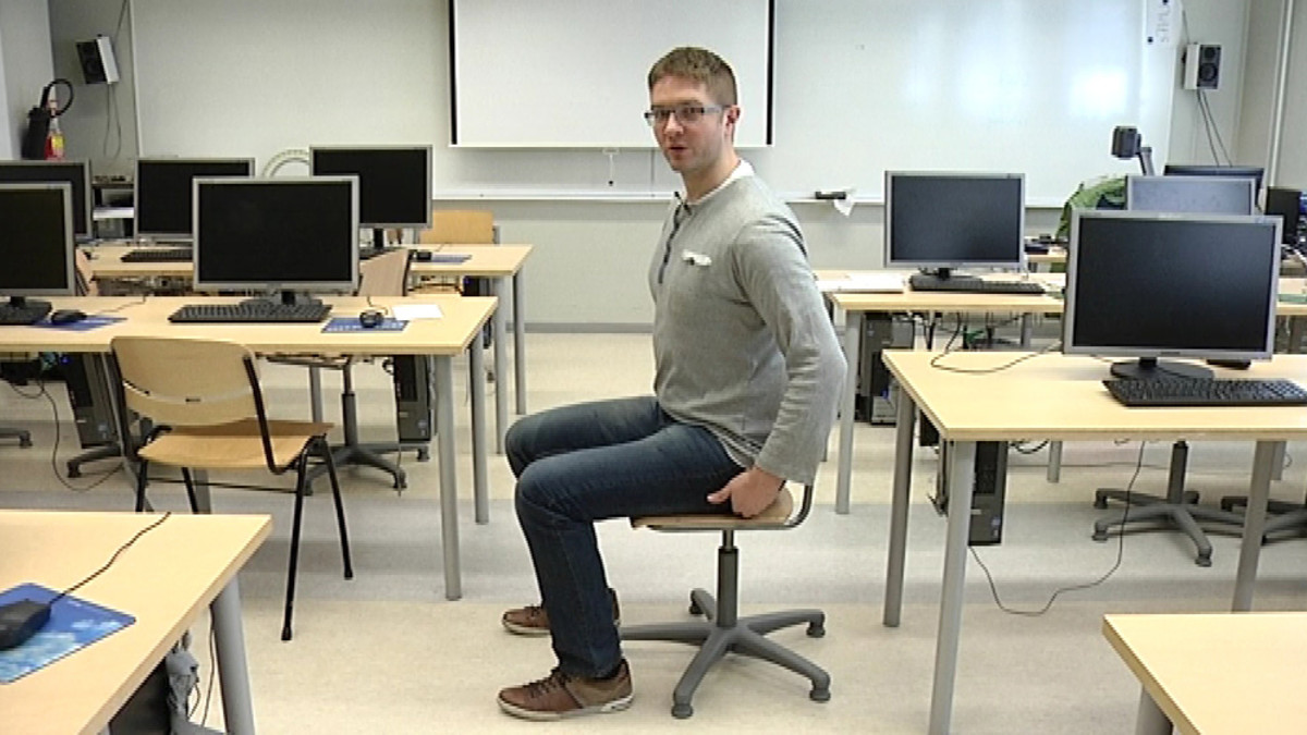 Kuvassa fysioterapeutti Rasmus Broberg näyttää hyvän istuma-asennon.