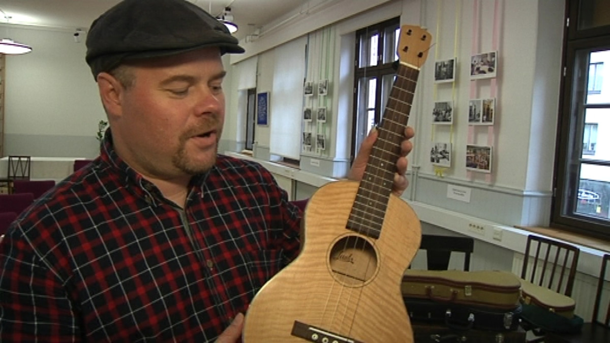Mies esittelee ukulele -kitaraa
