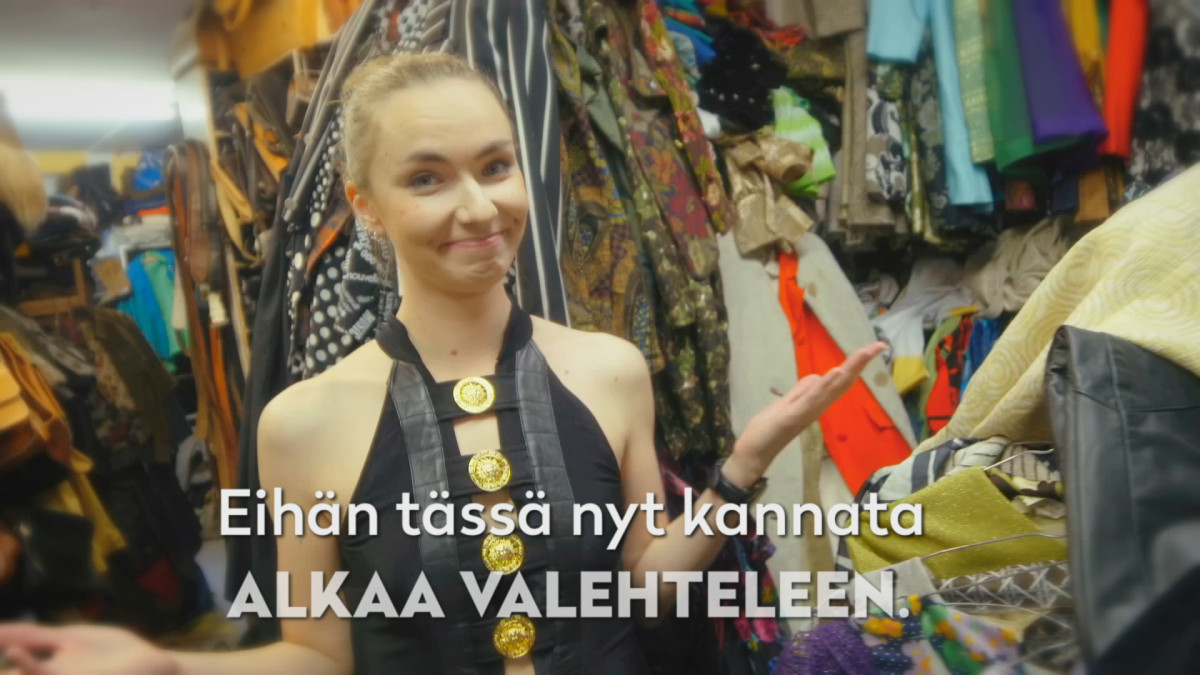 Toimittaja hymyilee kameralle vaateliikkeessä