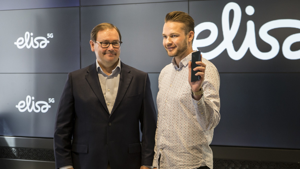Veli-Matti Mattila, Elisan toimitusjohtaja, antaa ensimmäisen 5G-puhelimen Harri Hellströmille