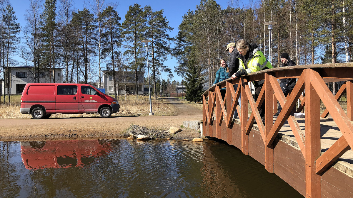 Kuvassa ihmisiä sillalla lammen äärellä