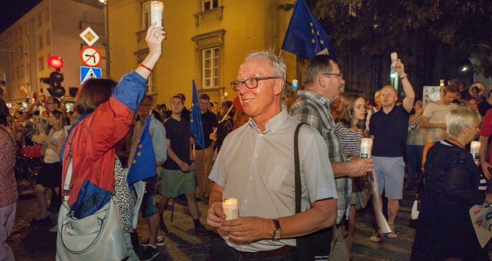Mielenosoittajia iltahämärässä, käsissä kynttilöitä ja EU-lippuja.