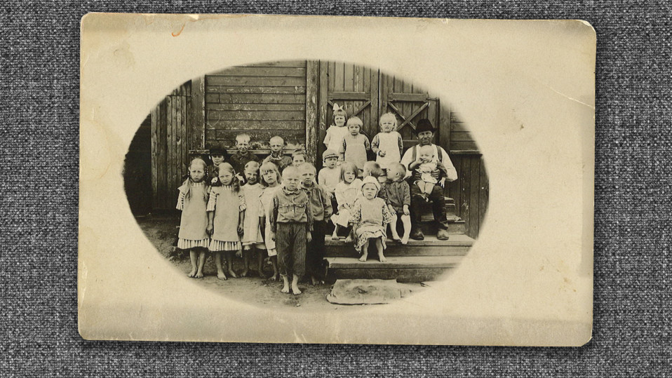 Mustavalkoinen kuva 1920-luvulta, 20 lasta rakennuksen portailla.