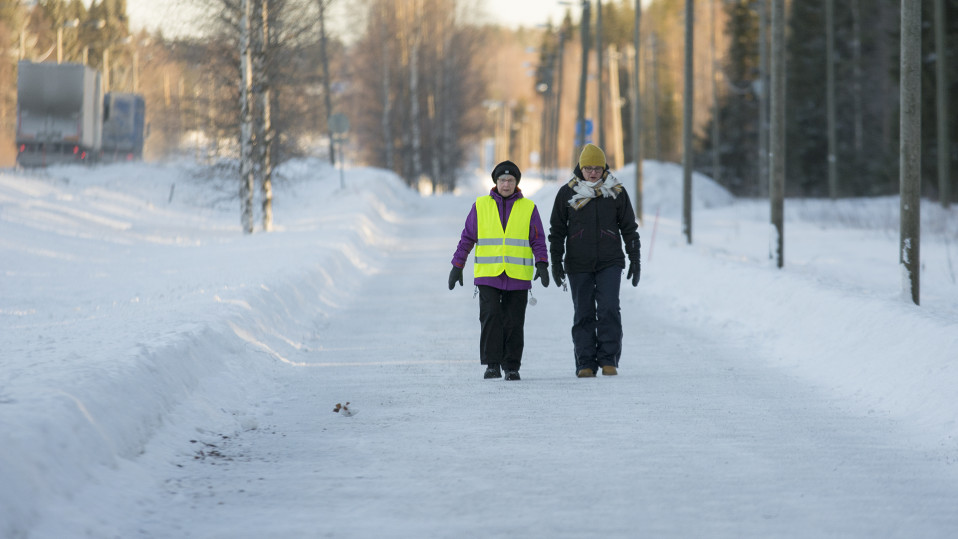 Kaksi naista kävelee lumisella kävelytiellä.