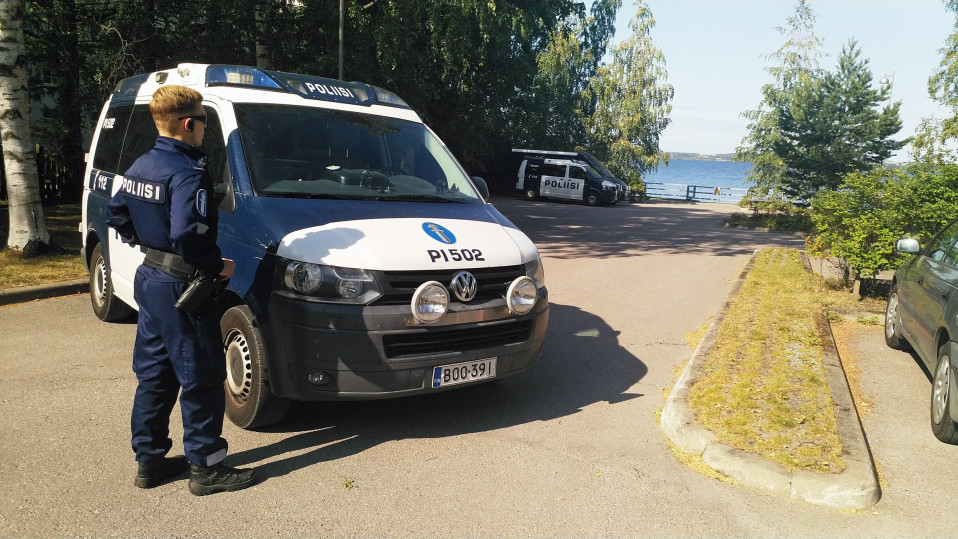 Poliisi seisoo poliisiauton vieressä ja katsoo Näsijärvelle