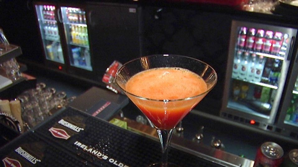 Kuvassa oranssi drinkki baaritiskillä