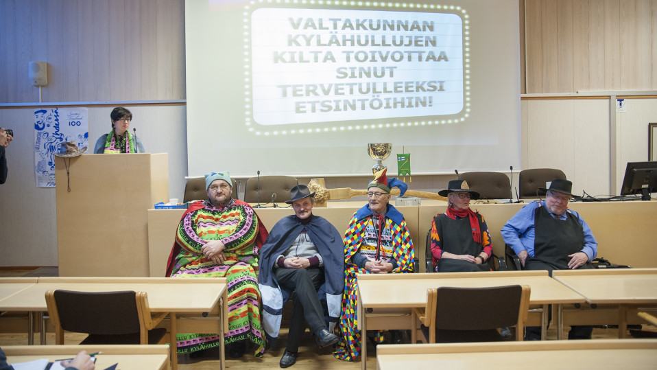 Viittoihin pukeutuneita ihmisiä rivissä puhujanpöntön edessä.