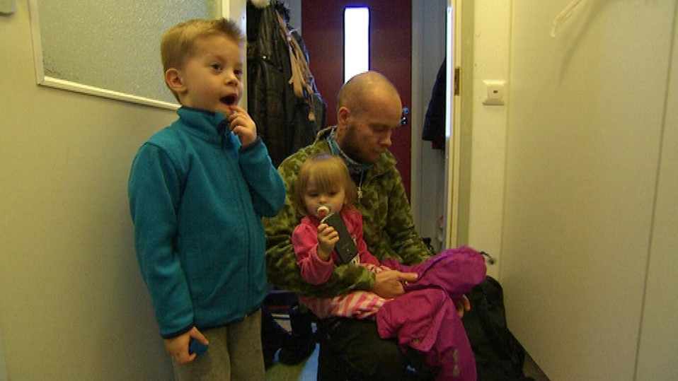 Isä pukee lapsille ulkovaatteita.