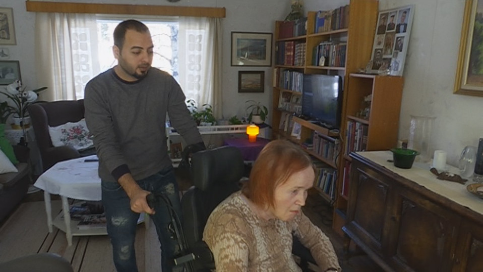 Irakilainen turvapaikanhakija auttaa liikuntakyvytöntä Eeva Mikkolaa Rovaniemellä.