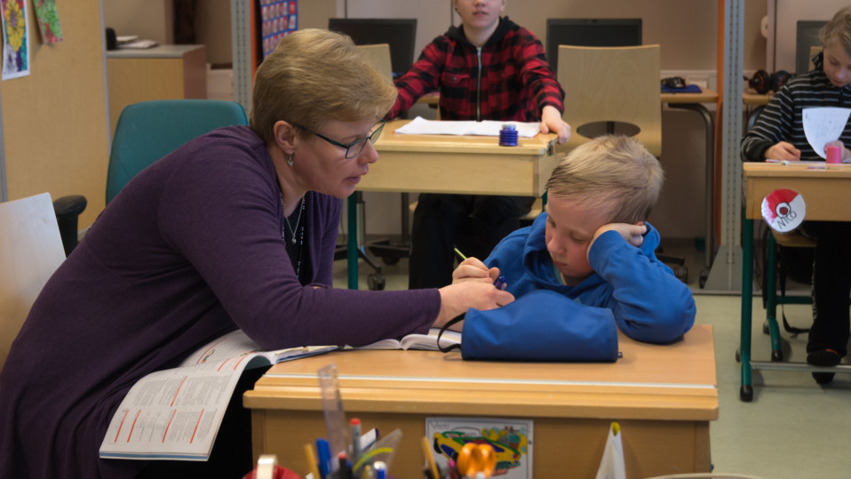 Erityisluokanopettaja Tarja Leinonen opastaa Veeti Saarenpäätä koulutehtävässä.