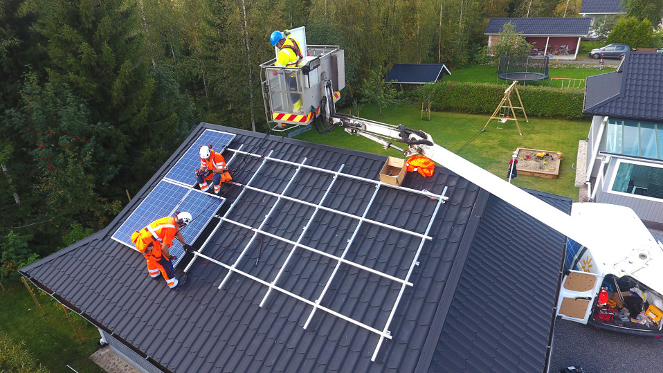 Miehiä asentamassa aurinkopaneeleja katolle.