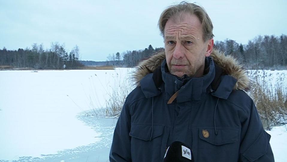 Mies seisoo järven ja mikrofonin välissä