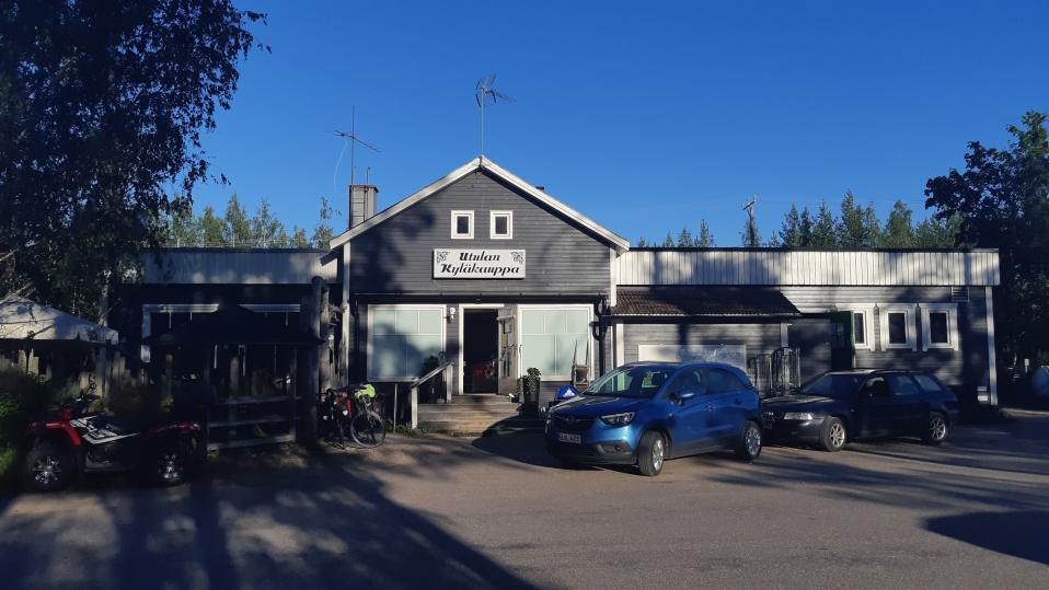 Utulan kyläkaupan harmaan puurakennuksen edustalla on muutamia autoja