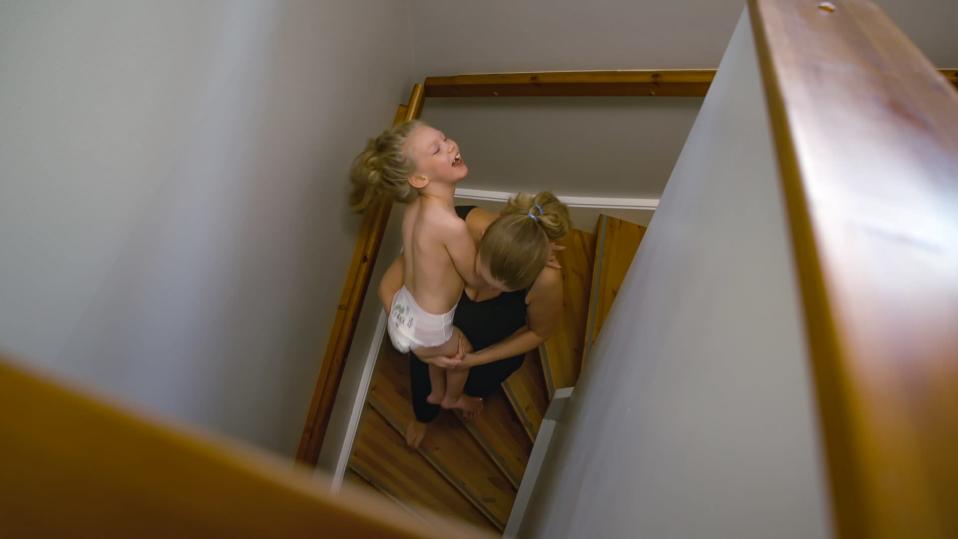 Äiti kantaa kehitysvammaista lastaan portaissa.