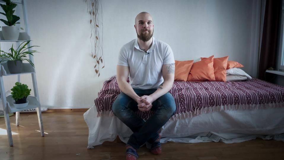 Markus Poikonen istuu sängyn laidalla.