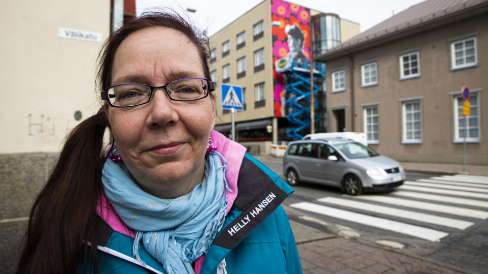 Kirsi Virtanen Riihimäen keskustassa, taustalla näkyy Maija Isolan unikkokuviota esittelevä muraali.