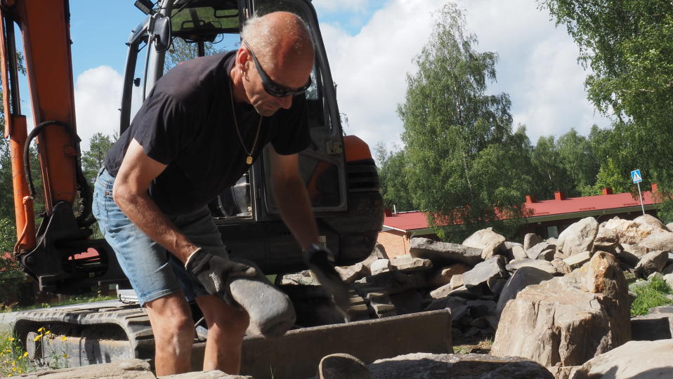 Mies laittaa kiven kiviaidan päälle