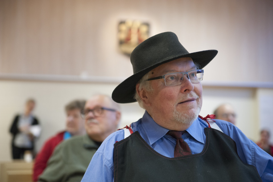 Hattupäinen mies katsoo eteenpäin.