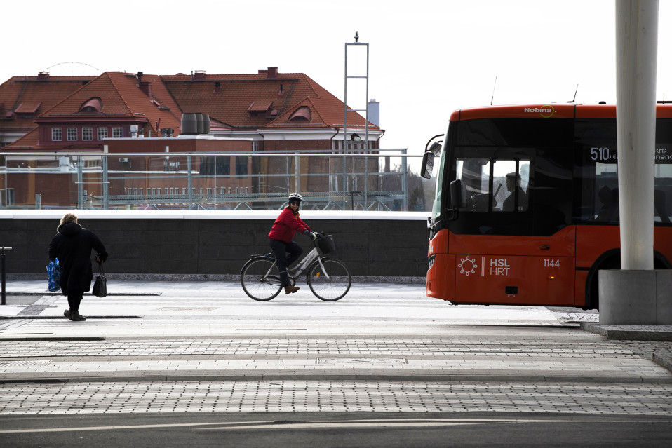 Jalankulkija, pyöräilijä ja linja-auto Pasilassa.
