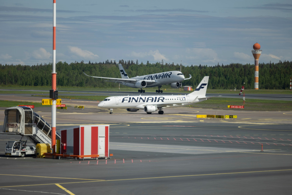 Kaksi Finnairin sinivalkoista konetta Helsinki-Vantaan lentokentällä, etualalla lentokenttäkalustoa.