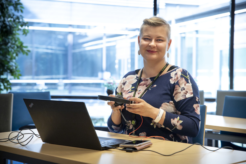 Mari Kivijärvi istuu kuulokkeet kädessään.