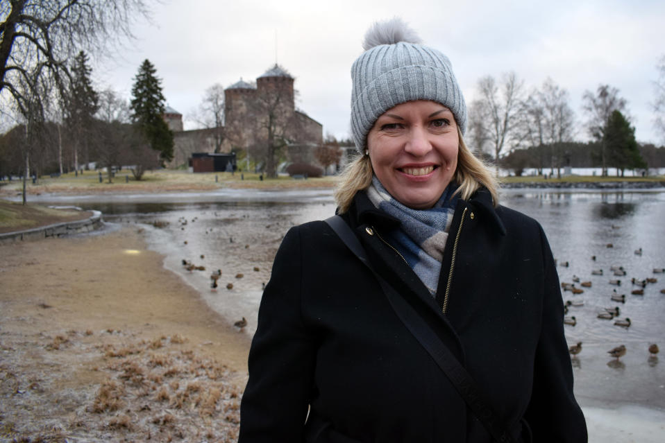 Savonlinnan kaupungin kaavoituspäällikkö Päivi Behm hymyilee iloisesti Olavinlinnan edustalla.