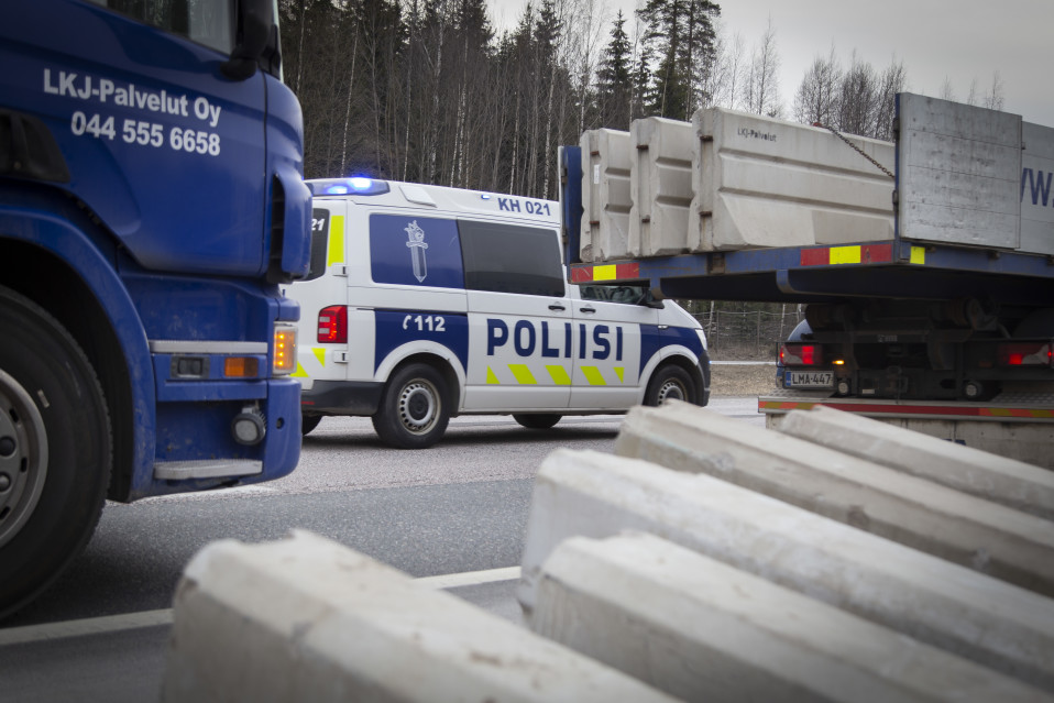 Poliisiauto vahtii liikennettä kun rakennusmiehet asentavat betoniporsaita Valtatie 3. tiesululle 27.3.2020.