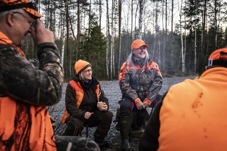 Hirvenmetsästäjiä nuotiolla. Keskellä kaksi naista.