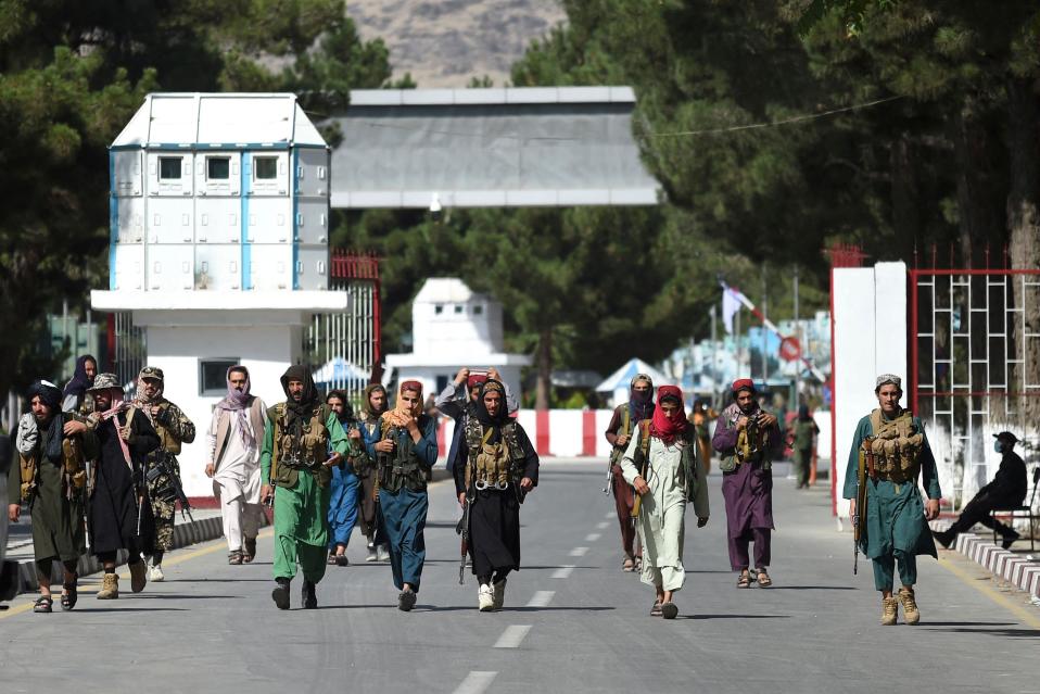 Talibankrigare promenerar vid huvudingången till Kabuls flygplats.