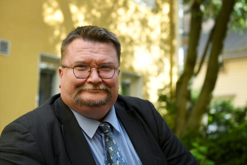 Arto Luukkanen ulkona keltaisen kivitalon edessä, lähikuva.