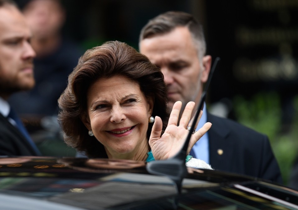 Silvia vilkuttaa lehdistölle, taustalla kaksi turvamiestä.