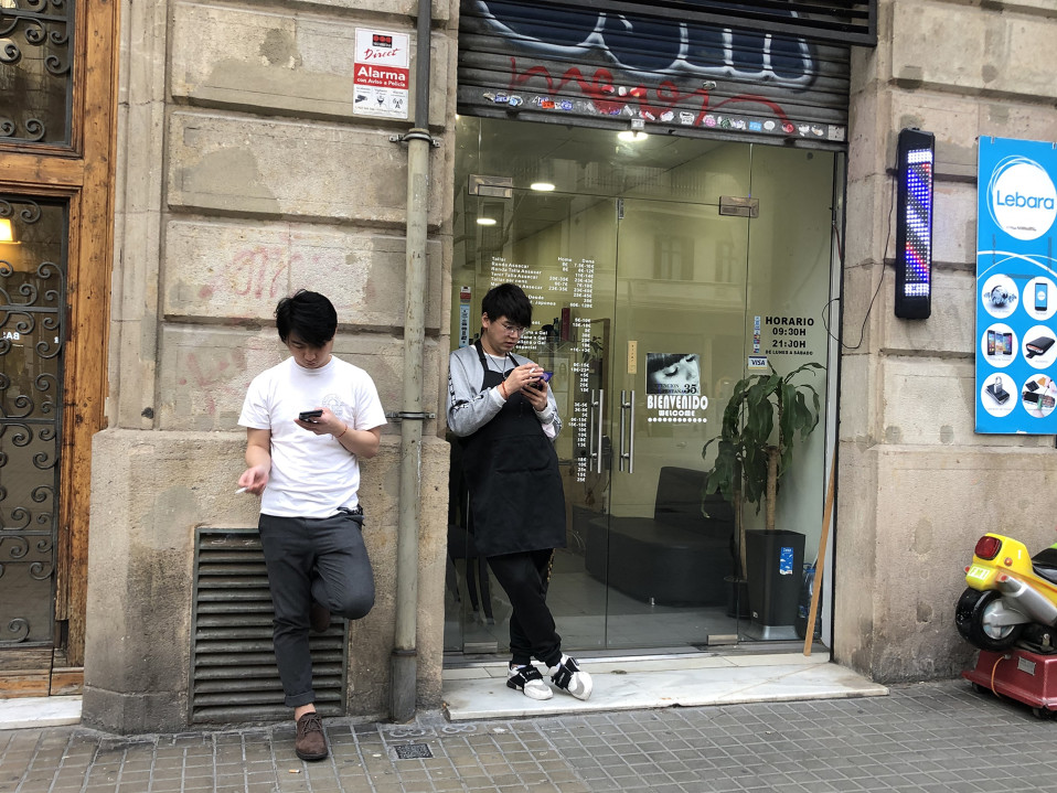 Barcelonassa kiinalaiset kynsihoitajat tupakoivat liikkeen edessä hiljaisena päivänä.