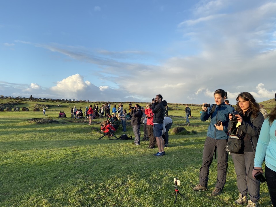 Turisteja kameroineen odottamassa auringonnousua Ahu Tongarikin moai-patsailla.