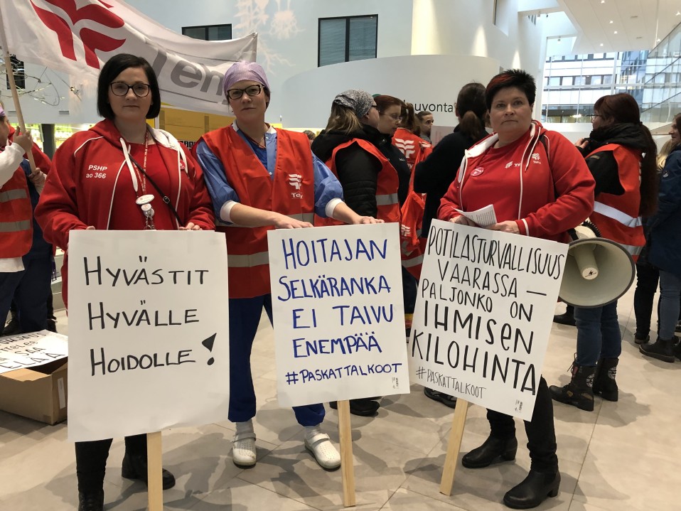 Hoitajat pitävät mielenosoituskylttejä.
