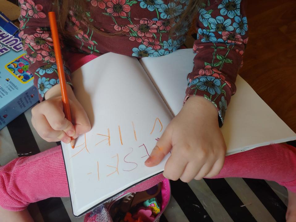 Elvi Sihvonen kirjoittaa tehtävävihkoon.
