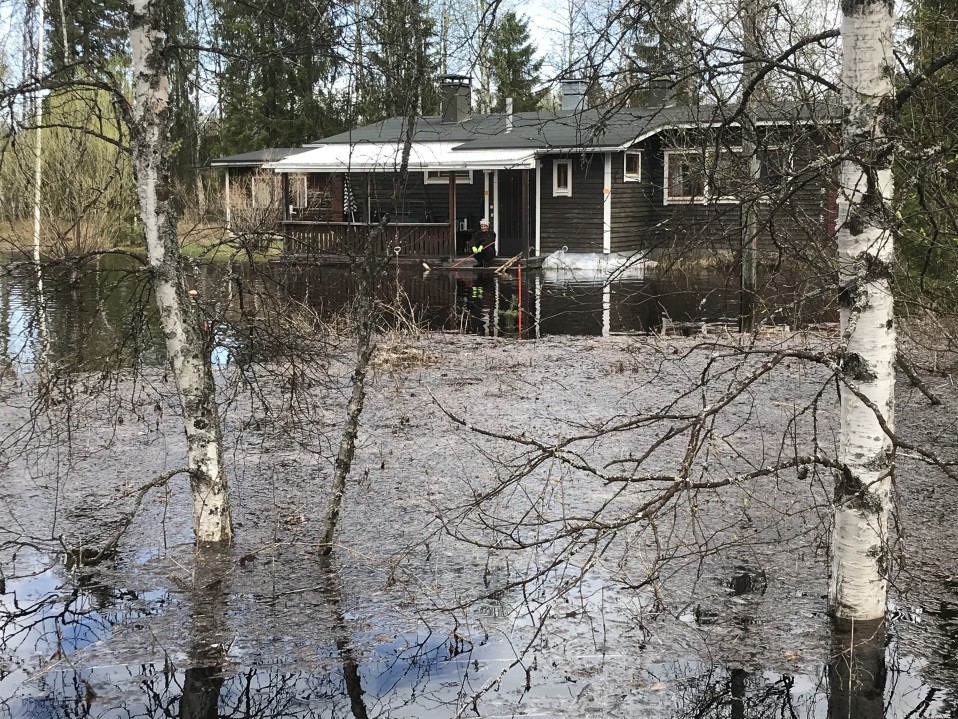 Markku Lemmetty tulvaveden ympäröimän mökkinsä portailla