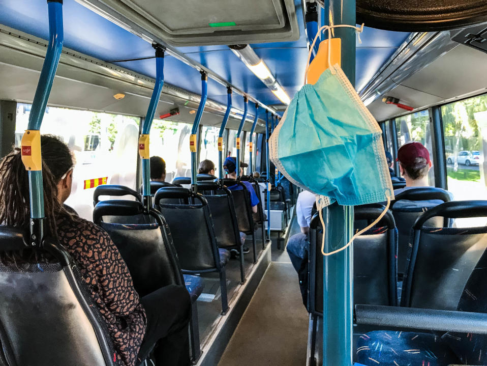 Hengityssuojain roikkuu bussissa.