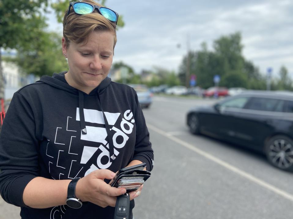 Kuvassa Kuhmoisten kunnanvaltuuston puheenjohtaja Minna Korppila katsoo kännykkäänsä Kuhmoisten keskuskadun varrella. Hän on perustanut Face Bookiin kimppakyytiryhmän