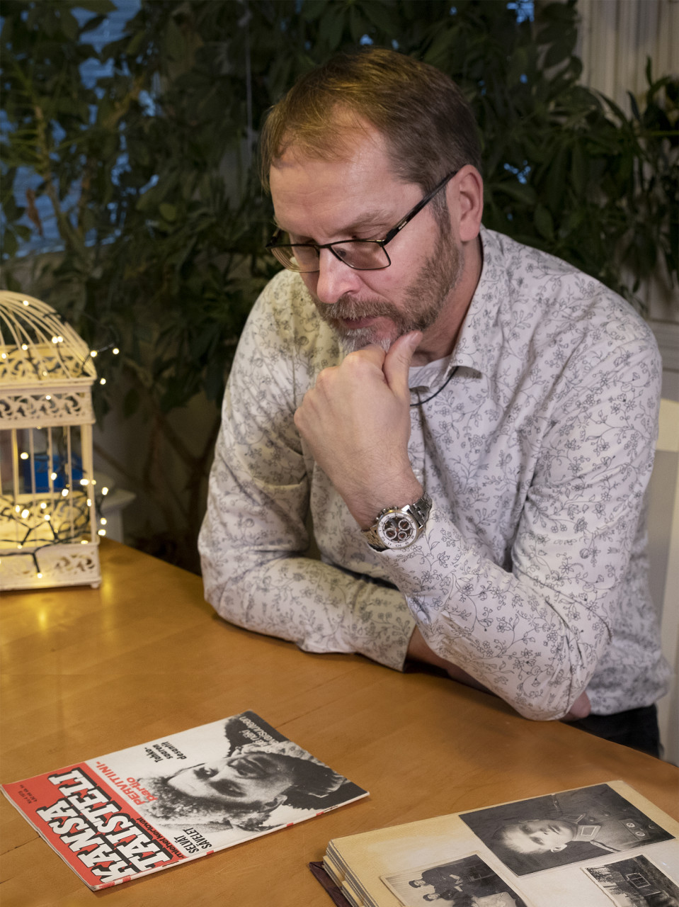 Mika Koivunen istuu pöydän äärellä ja katselee Kansa taisteli -lehteä.