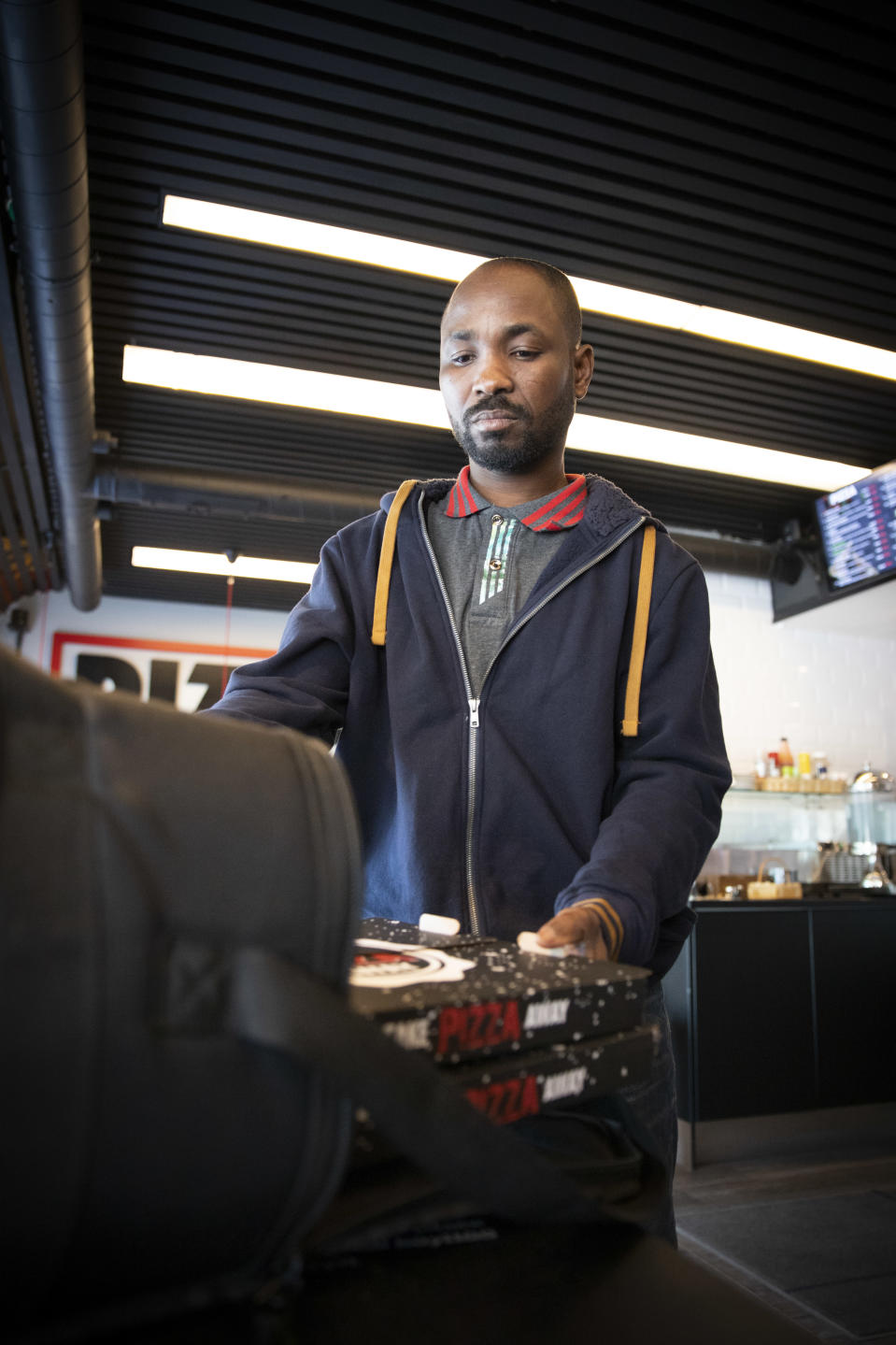 Muhammed Musah pakkaa pitsalaatikoita kuljetuslaatikkoon ravintolassa.