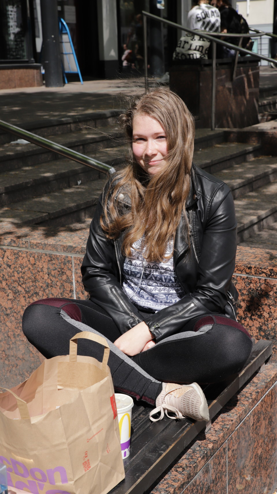 Susanna Ettala istuu pikaruokapussin kanssa kaiteella.