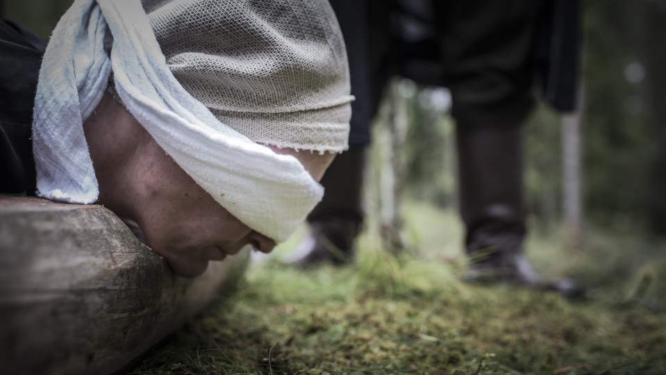 Mestauksen dramatisoinnissa kuolemantuomittu odottaa pölkyllä.
