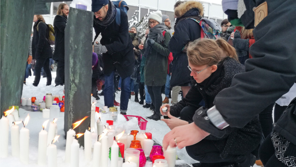 Ihmiset asettavat kynttilöitä patsaan juurelle