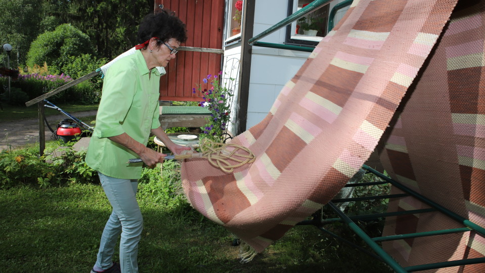 Siivousyrittäjä Aini Lehtosalo tamppaa mattoa.