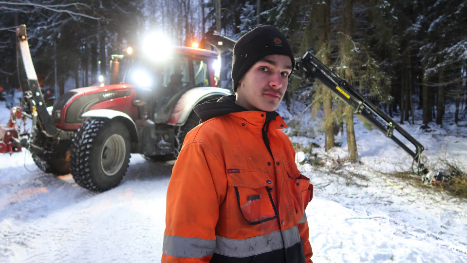 eemeli hursti seisoo metsätiellä, taustalla metsätraktori.