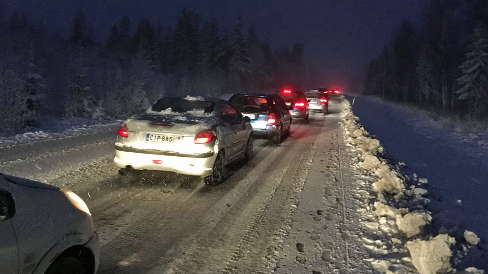 Autoja jonossa lumisella maantiellä.