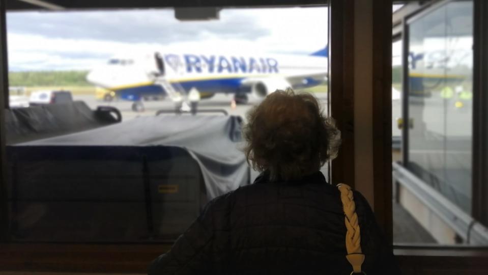 Iäkäs nainen seuraa ikkunasta Ryanairin koneen laskeutumista