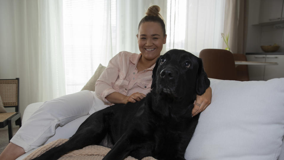 Oululainen Jenni Määttä ja hänen labradorinnoutajansa istuvat sohvalla.