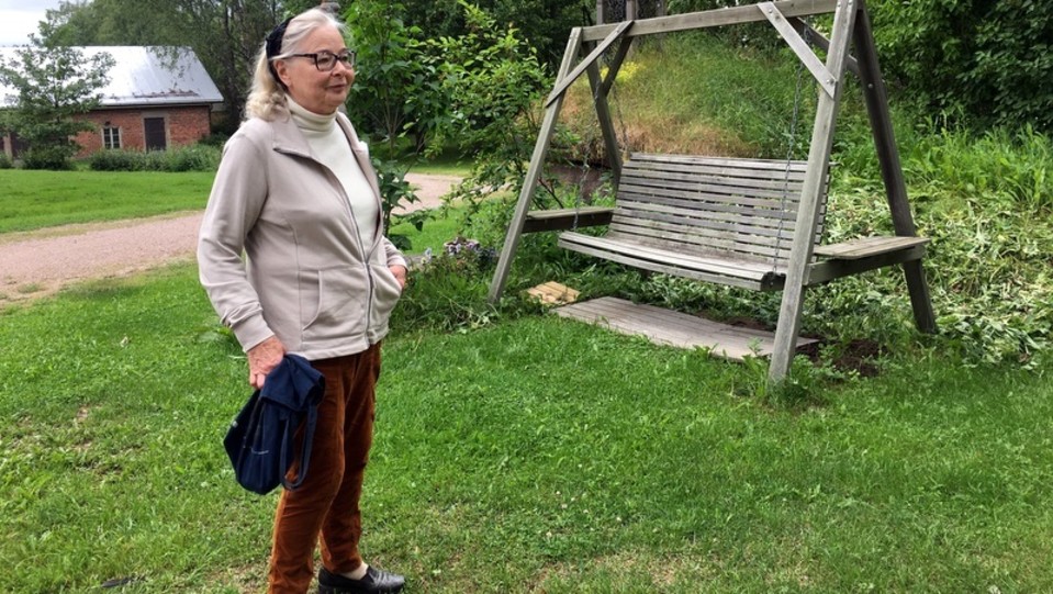 Nainen pihakeinun edessä.