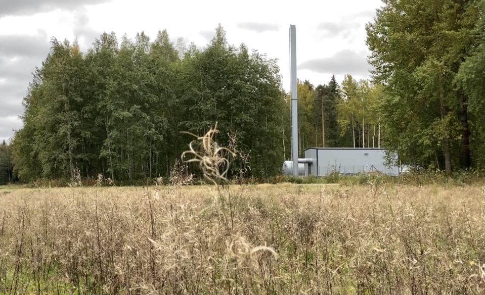 Pieni varalämpövoimala. Edessä niittyä, voimalan ympärillä metsää.